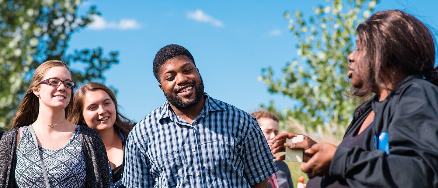 Woman talking to a group of students outdoors